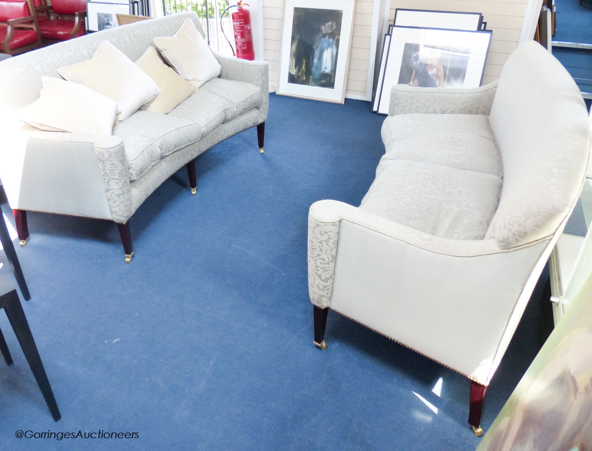 A pair of George III style eau de nil silk damask concave fronted two seat sofas, on square tapered mahogany legs with brass casters, approximately 188 cm wide